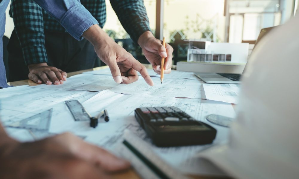 Image of engineer meeting for architectural project working with partner and engineering tools on workplace.